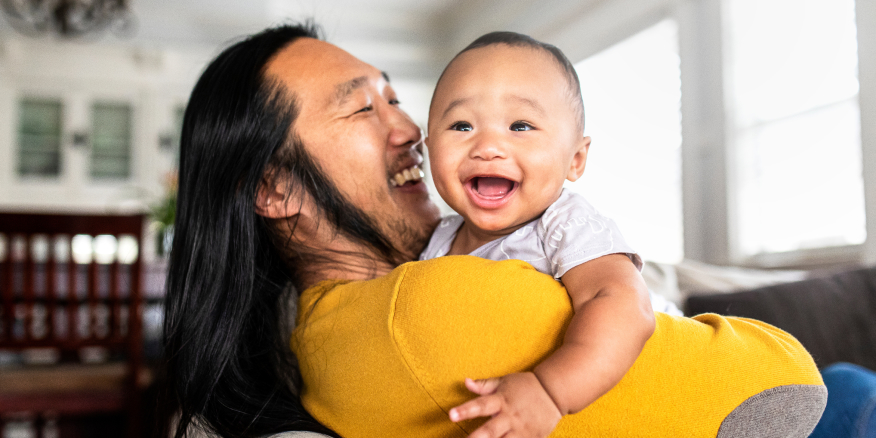A smiling man holding a happy baby